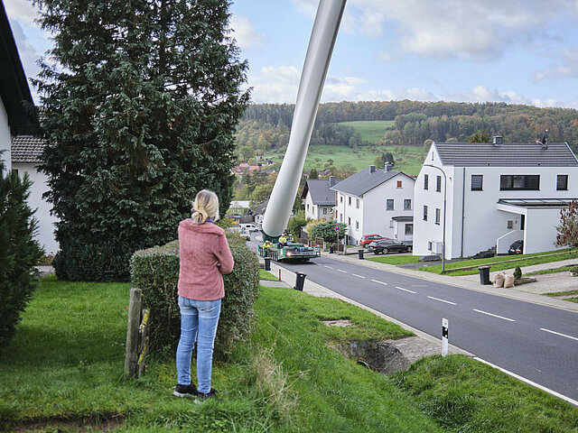 Frau beobachtet Anlieferung von einem Rotorblatt in ihrer Straße.