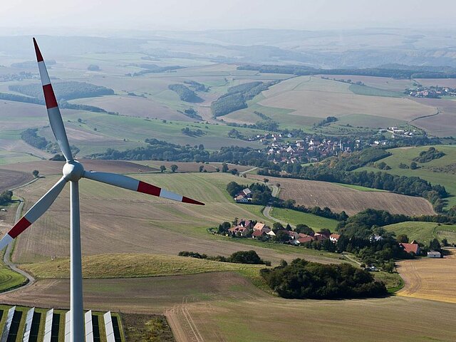 Windenergie-Anlage am Rande eines Dorfs.
