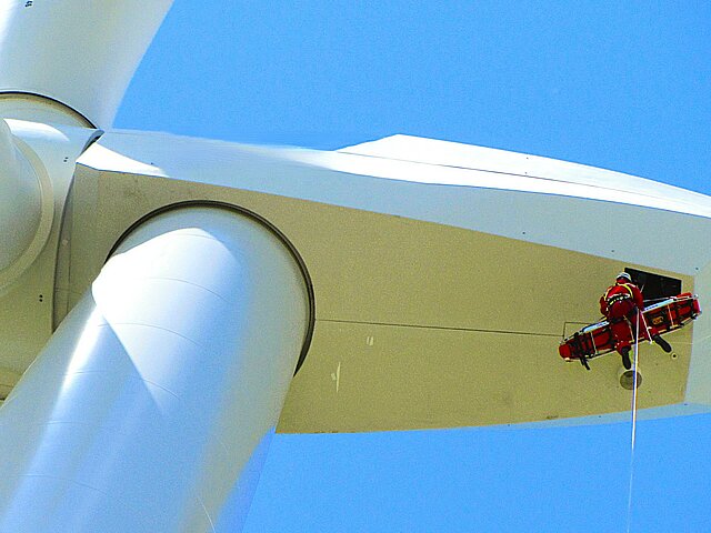 Höhenrettung aus der Krankluke einer windenergieanlage mit einer Rettungskraft und einem verletzen Servicemitarbeitenden, der liegend in der Trage abgeseilt wird.
