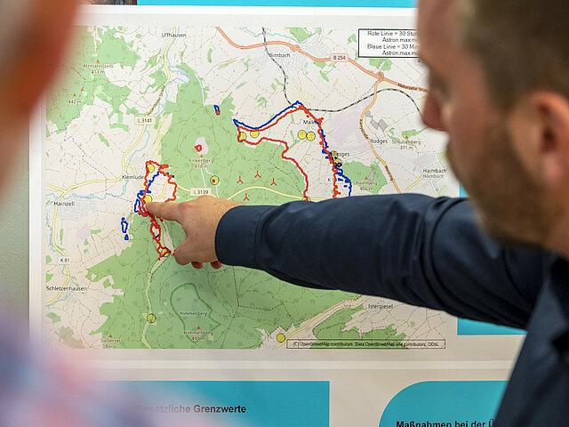 Ein Projektentwickler zeigt einem Anwohner auf einer Karte den Standort des geplanten Windparks.
