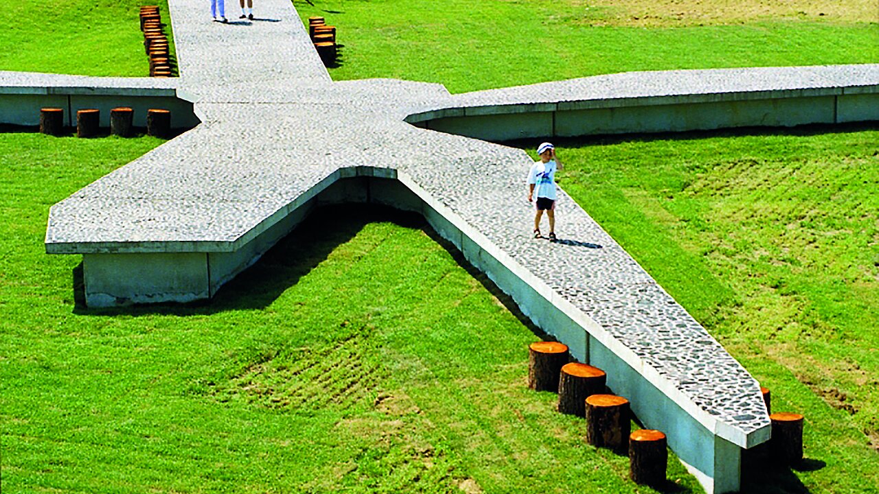 Die Holzstämme symbolisieren nicht nur Sitzmöglichkeiten sondern stehen auch für die Energieerzeugung der Windenergie-Anlage. Ein Kind läuft über den Tisch aus Kohle.